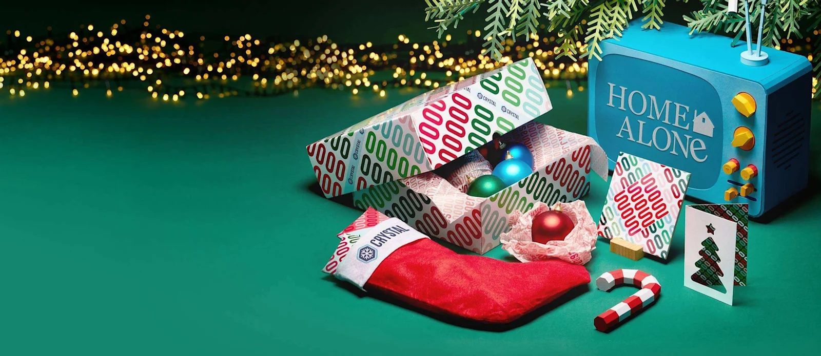 Geschenkschachtel mit Christbaumkugeln, Weihnachtsstrumpf, Zuckerstange und Karten unter dem Christbaum