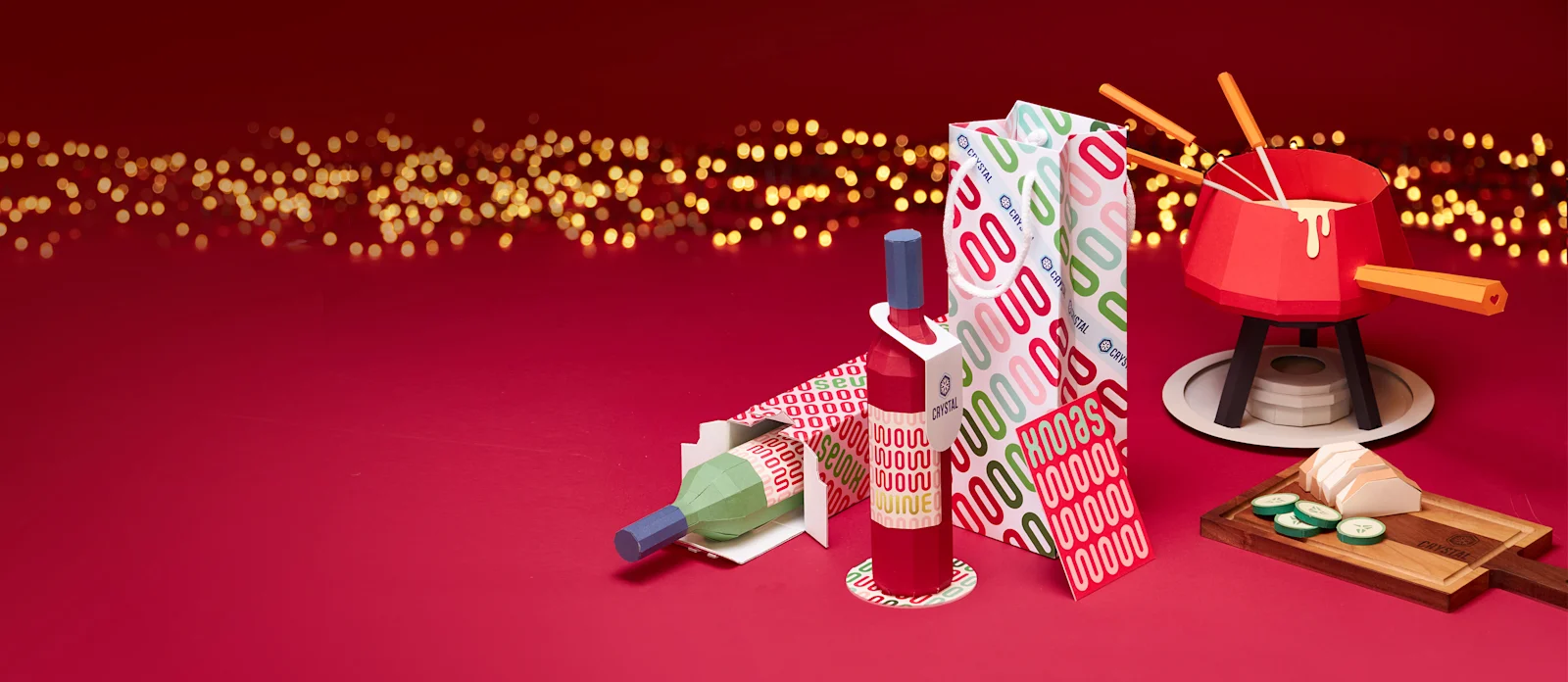 Weinflasche mit eigenem Etikett, Weintasche, Geschenkschachtel und Fondue-Topf auf rotem Hintergrund